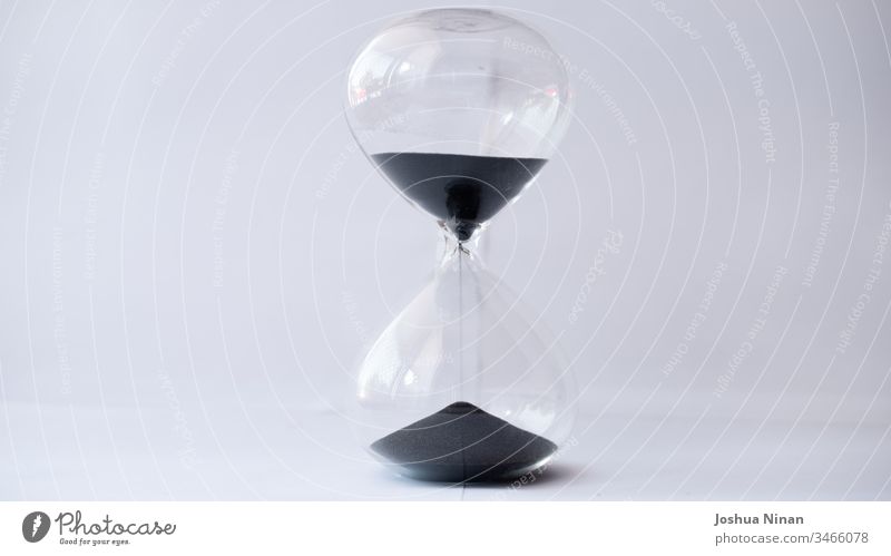 Hourglass with black sand running out background black sand hourglass clock concept countdown deadline egg timer flowing future measure of time measurement