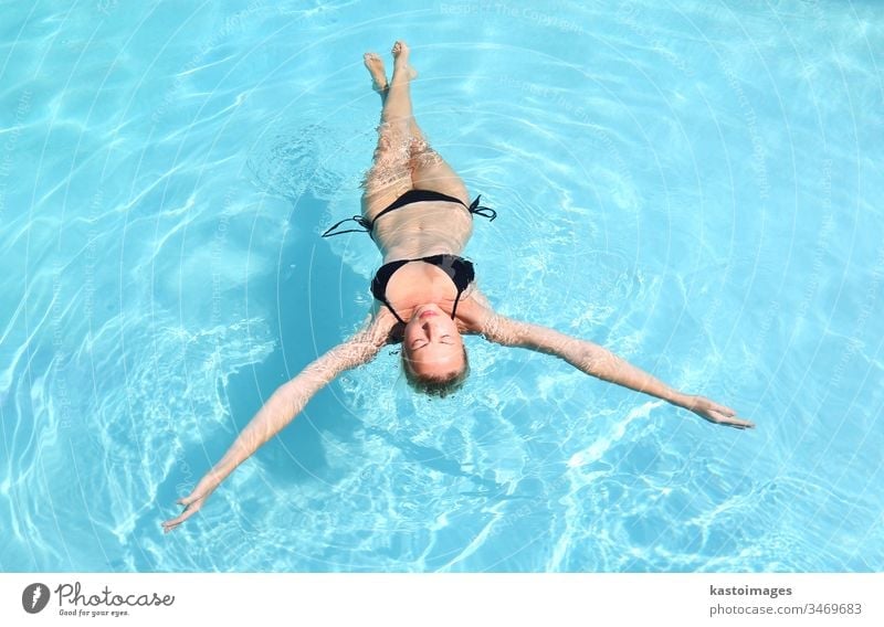 Woman in bikini lounging in transparent chair by pool, Stock Photo