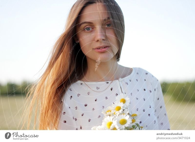 Beautiful young woman enjoying a field of daisies, beautiful girl relaxing  outdoors, having fun, holding bouquet of daisies, happy young lady and  spring-green nature, harmony concept. - a Royalty Free Stock Photo