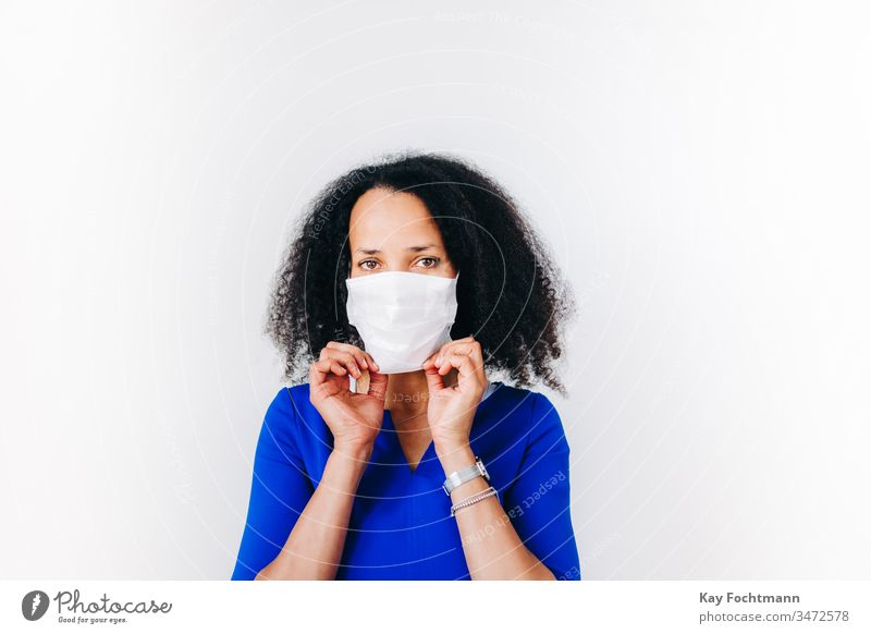 black woman putting on a surgical mask african-american black hair blue blue shirt coronavirus covid-19 curly hair day disease face fear female flu front view