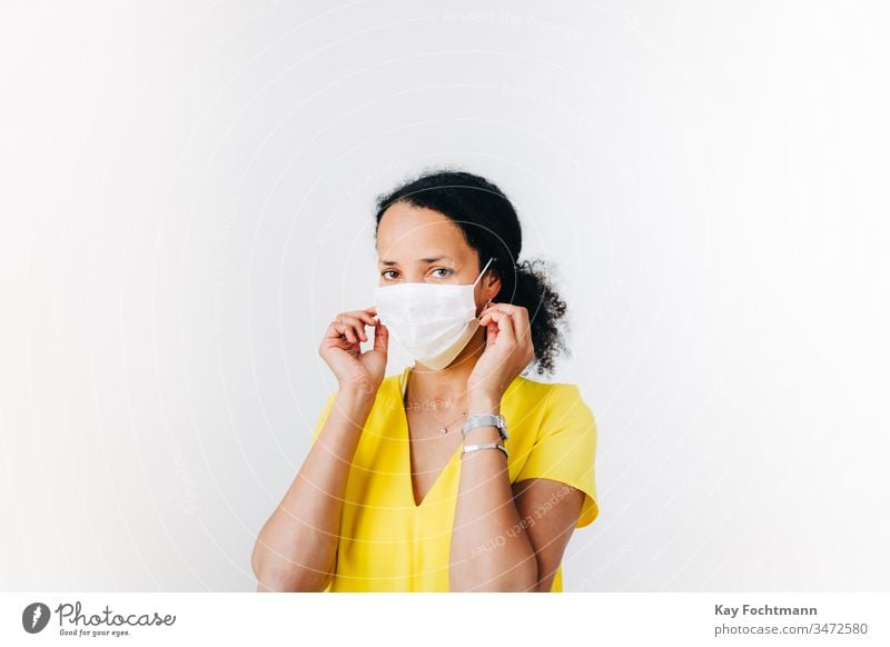 black woman putting on a surgical mask african-american black hair blue shirt coronavirus covid-19 curly hair day disease face fear female flu front view health