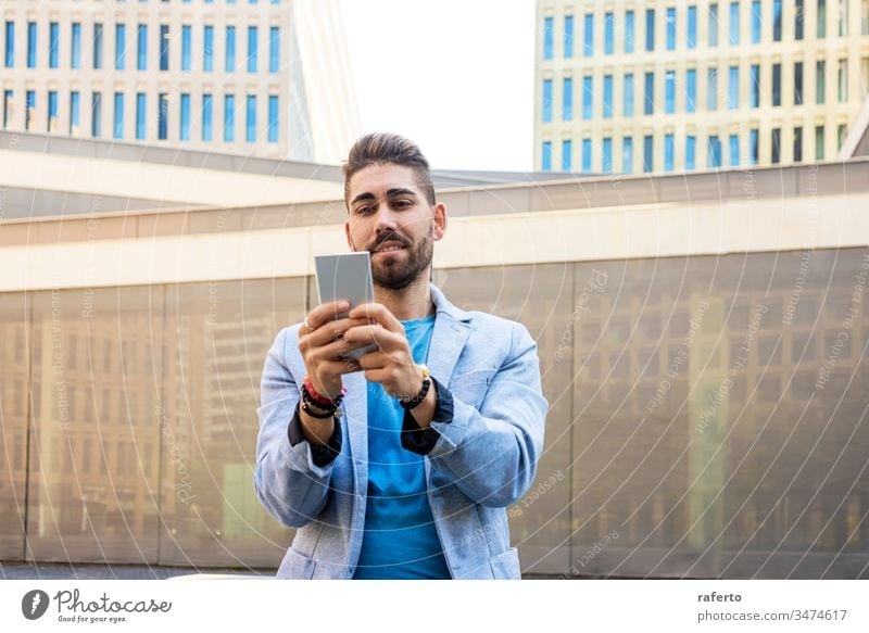 Portrait of Handsome bearded young man smiling when he is using his mobile phone style guy sunglasses hipster 1 photogenic technology writing adult standing