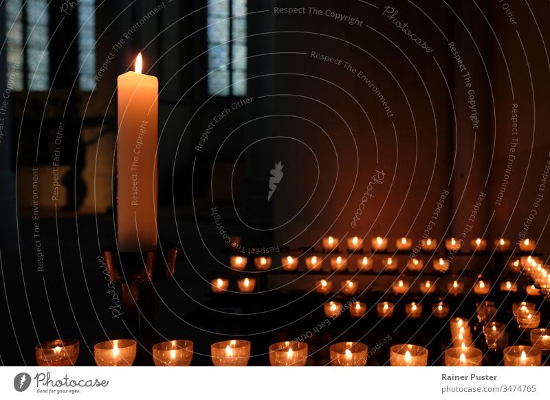 One large candle and many small candles in a church candlelight inside a church religion faith belief religious Religion and faith christianity hope prayer