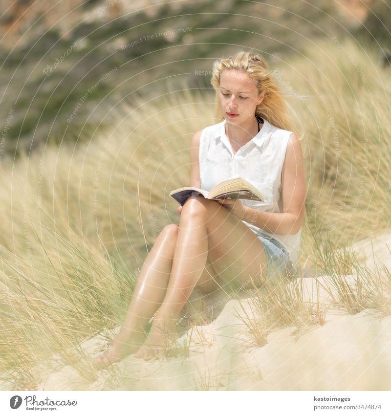 Woman reading book, enjoying sun on beach. summer woman nature free happy carefree relax wind freedom happiness relaxation leisure island young wellness