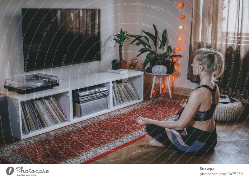 Young woman meditating in the living room. Staying healthy at home. attractive beautiful beauty boho chic boho interior calm care comfortable exercise female