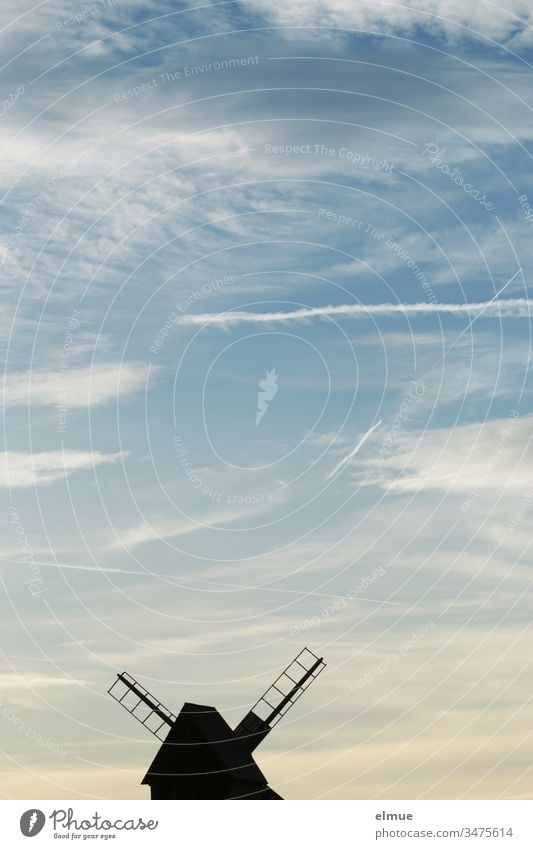 Windmill at the lower edge of the picture in silhouette form and sky with contrails bock windmill Vapor trail Wood fair weather cloud Grand piano Romance