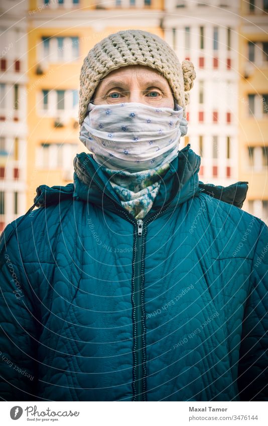 A poor elderly woman wears a homemade mask to protect herself from viruses adult airborne breathing buildings city contagion contagious corona coronavirus cough