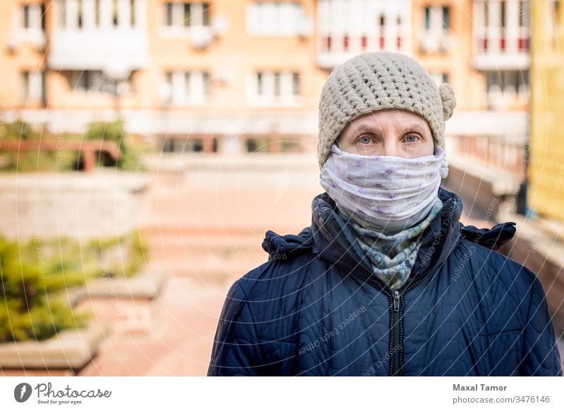 A poor elderly woman wears a homemade mask to protect herself from viruses adult airborne breathing buildings city contagion contagious corona coronavirus cough