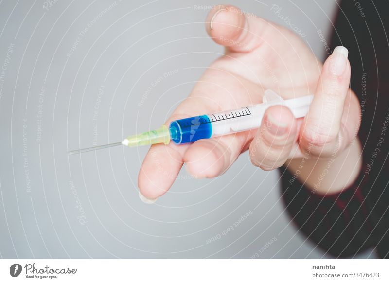 Womans hand holding a syringe covid 19 flu influenza mask coronavirus pandemic epidemic vaccine investigation studio treatment medicine drug illness