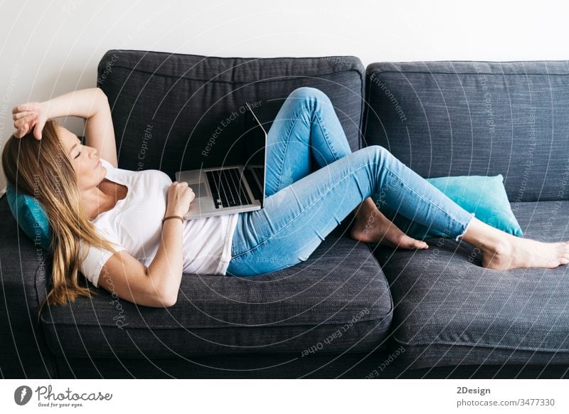 Pretty long haired female sitting on sofa with portable computer working remotely from home. woman using room relaxation smile typing communication modern