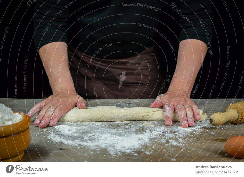 Man hands kneading bread dough on a wooden table with black background food flour wheaten meal loaf cookery organic gourmet cooking bakery healthy male cuisine