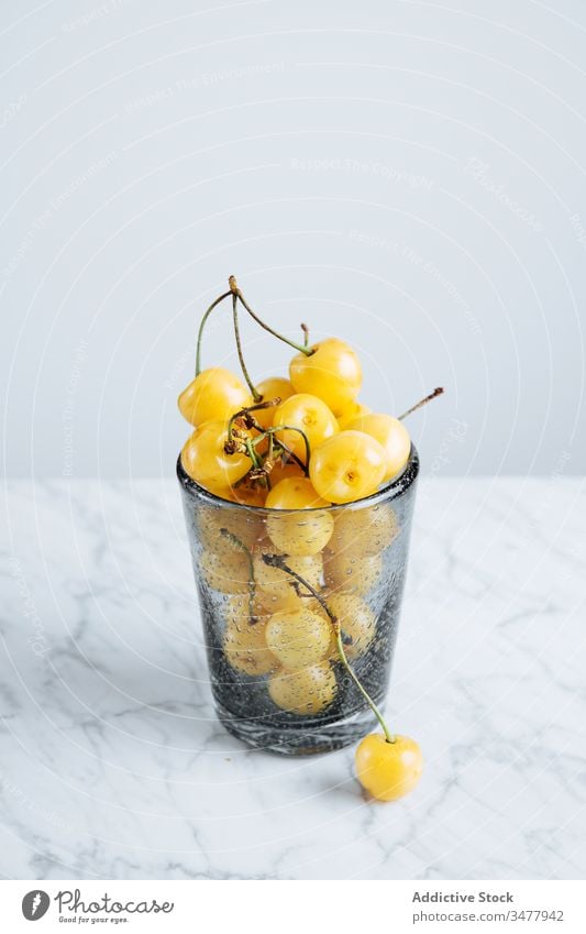Glass with yellow cherries on table cherry berry fruit fresh ripe natural food healthy glass full plant stalk vitamin sweet tasty delicious raw season summer