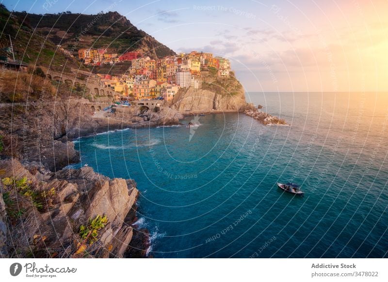 Wonderful scenery with small colorful town on rocky coast washing by calm ocean water during sunset sea boat idyllic cliff sky shore coastline paradise tourism