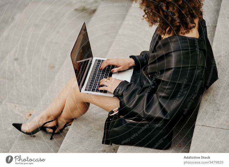 Smart trendy woman in leather suit browsing laptop on steps businesswoman using project stair street sit typing city retro outfit female black jacket cool 80s