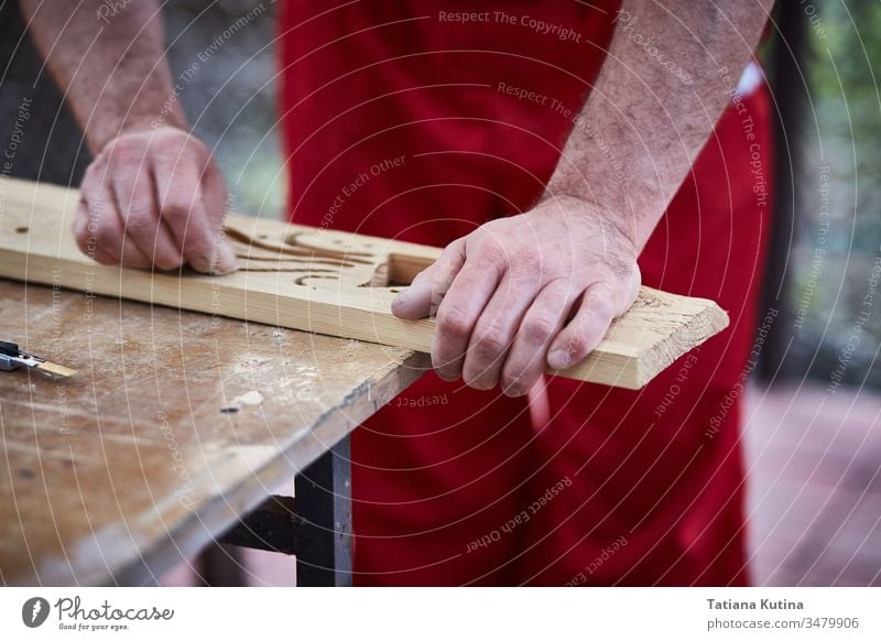 Closeup of male hands carpenter using sandpaper to sand wooden detail. carpentry closeup craft craftsman diy industry job sanding tool worker workshop business