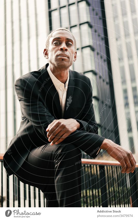 Confident black businessman leaning on railing confident modern street urban ethnic city suit male hand in pocket professional elegant entrepreneur success