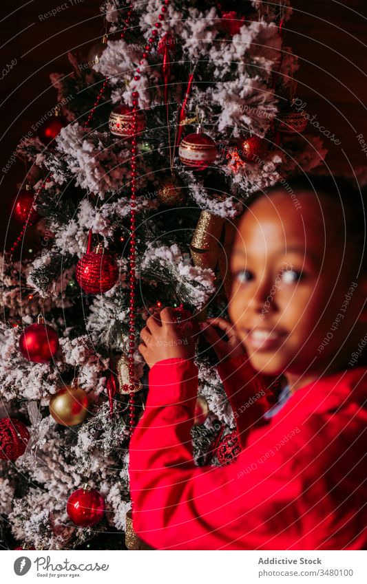 Happy little girl decorating Christmas tree kid christmas decorate tradition home rustic ethnic smile happy casual cheerful positive female enjoy festive black