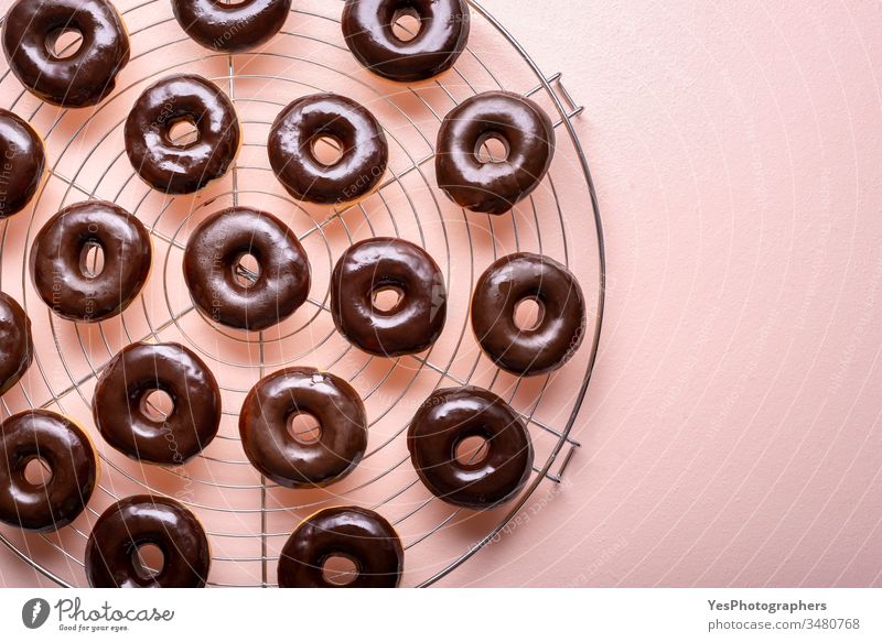 Hot donuts with melted chocolate on a cooling rack. Preparing choco doughnuts above view aligned background bakery carbs choco donuts chocolate glaze close-up