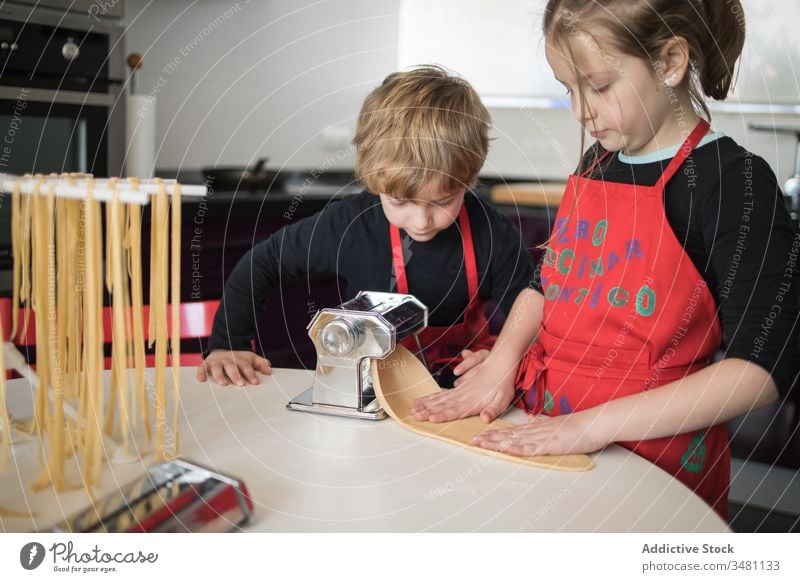 Kids preparing noodles at home kid pasta make machine together sibling kitchen homemade prepare cut sister brother children food apron cook culinary equipment