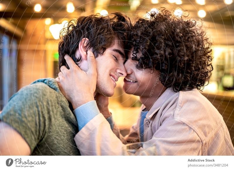 Multiethnic gay couple flirting during date in cafe table happy together cheerful friend boyfriend romantic affection partner kiss homosexual lover lgbt