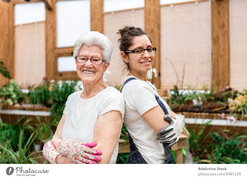 Confident female gardeners smiling for camera women positive work together smile hothouse plant elderly horticulture organic greenhouse happy care botany