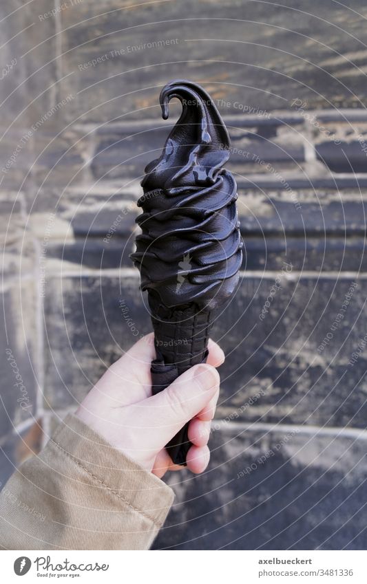 hand holding black soft serve ice cream cone made with activated