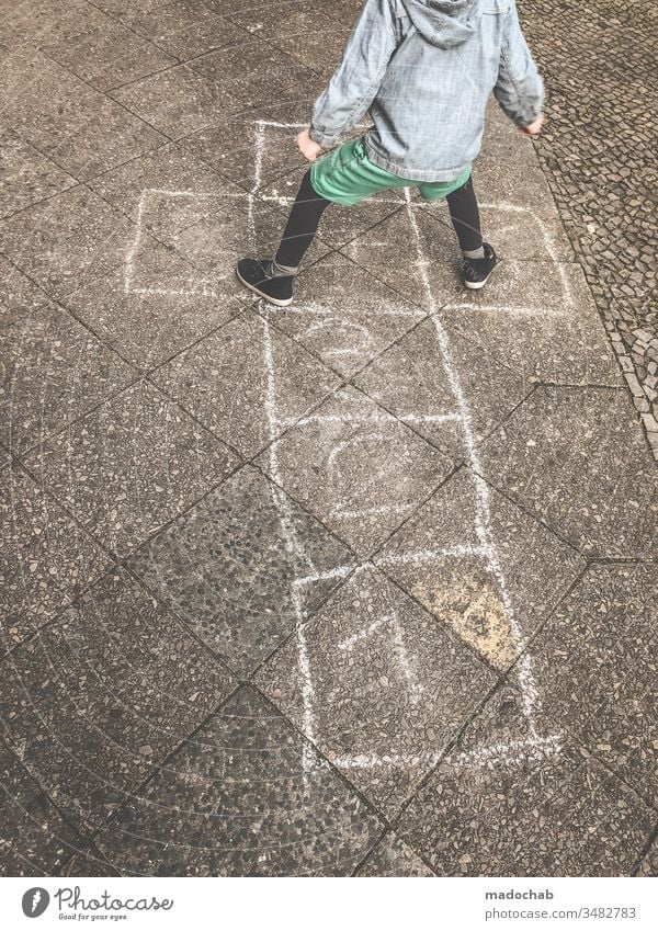 playing with the children's box - child jumps from number to number on chalk painted boxes - old children's game Hop Jump Chalk Child fun Exterior shot Playing