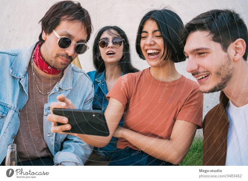 Group of friends watching something in smartphone. mobile friendship lifestyle portrait holding smart phone urban modern meeting joy enjoyment enjoying