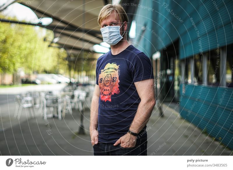 Portrait of a man with a protective mask standing in front of a building, biological danger from coronavirus: Covid-19 danger person Epidemic Protection Virus