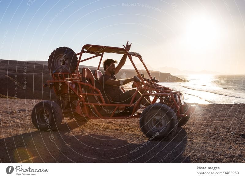 Man driving quadbike in sunset. beach adventure extreme sand sport vehicle outdoor fun ride ocean show rocking sign male quad racing dune buggy land vehicle