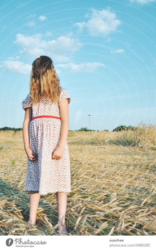girl in summer dress on a straw chopper with hair on her face Child Girl Summer Field acre Summer dress Infancy Hand Fingers Arm Sky Grain field Wild Movement