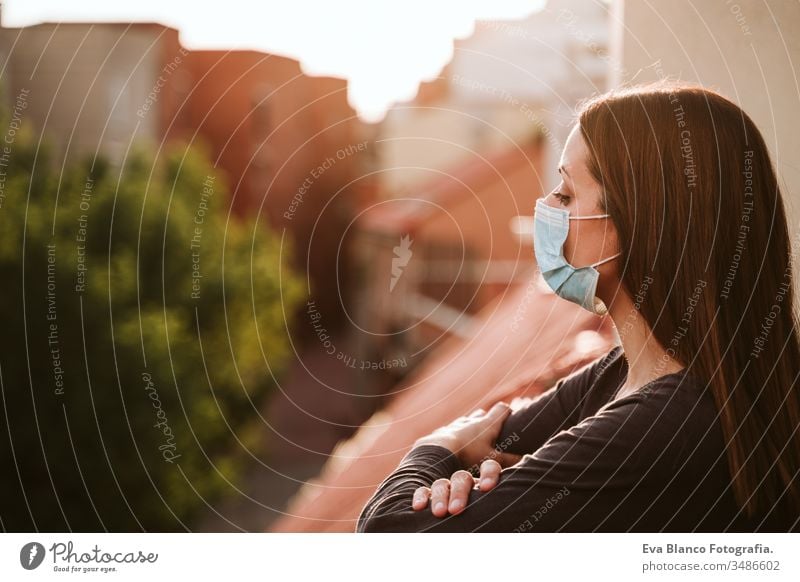 young woman at home on a terrace wearing protective mask and enjoying a sunny day. Corona virus Covid-19 concept coronavirus covid-19 indoors caucasian