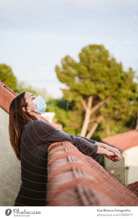 young woman at home on a terrace wearing protective mask and enjoying a sunny day. Corona virus Covid-19 concept coronavirus covid-19 indoors caucasian