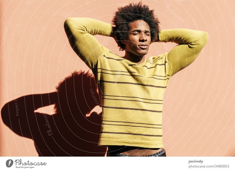Cuban black man enjoying the andalusian sun with his eyes closed millennial afro sunlight hair african male face adult portrait american person casual guy