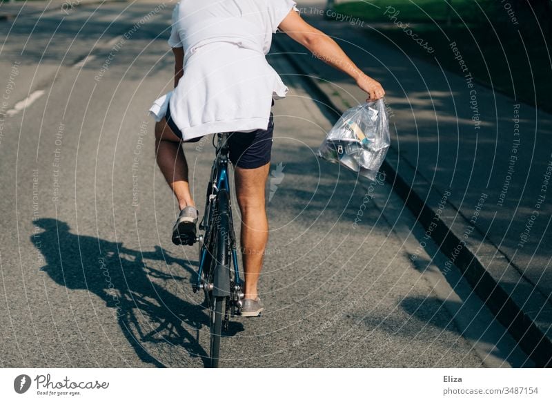 A man in summer on a bicycle with a bag full of metal garbage taking away garbage; recycling, waste separation Metal waste Recycling Bicycle cyclist Man Summer