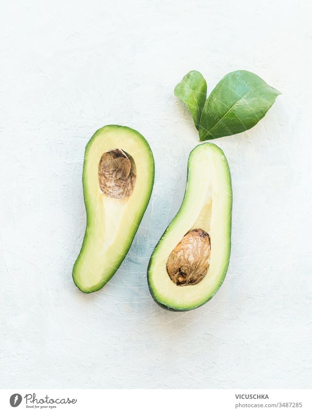 Avocado cut in half with green leaves on white table background, top view. Healthy food ingredient avocado healthy food antioxidant refreshment nutritious