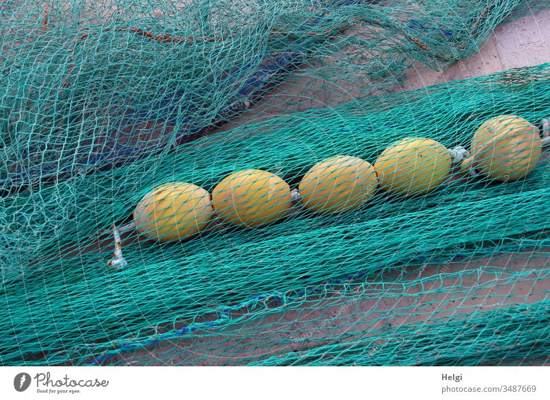 turquoise fishing nets with yellow floating balls are lying at the harbour  - a Royalty Free Stock Photo from Photocase