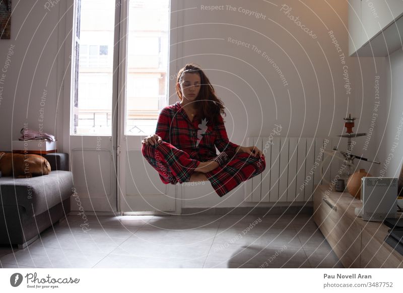 Young woman with pijama meditating while levitating at home harmony floating spirituality contemplation young concentration fly meditation sexy indoors girl
