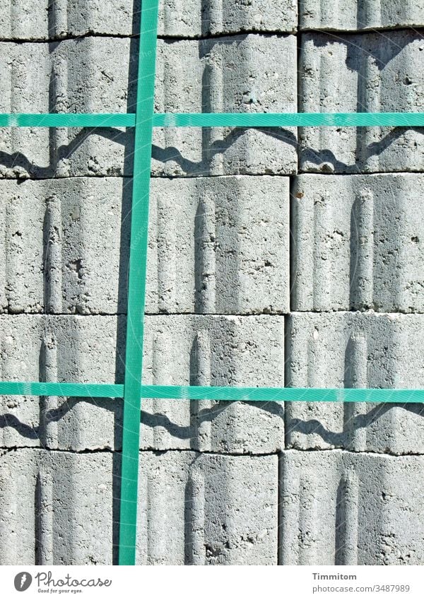 Close connection building material Paving stone Stack pallet Connection Plastic Plastic straps Gray green Light Shadow lines Deserted Stone Construction site
