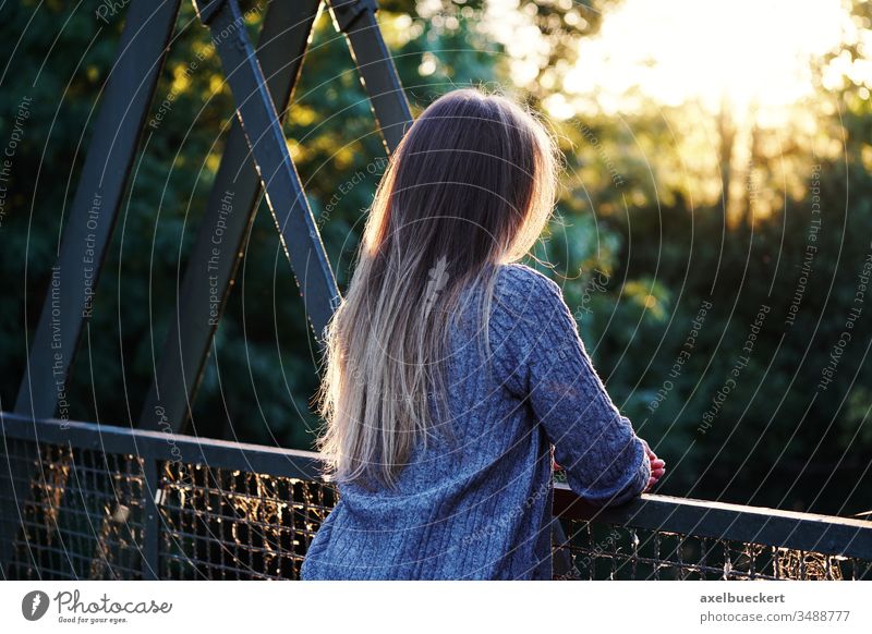 young woman stands alone at the bridge railing Woman Young woman on one's own Bridge railing Loneliness depression Fear of the future Rear view Unrecognizable
