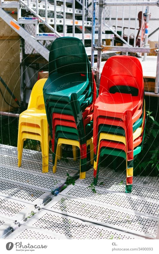 a stack of coloured chairs Chair variegated Stack stackable out Event Plastic chair plastic event Red Yellow Green Colour photo Deserted Exterior shot Day