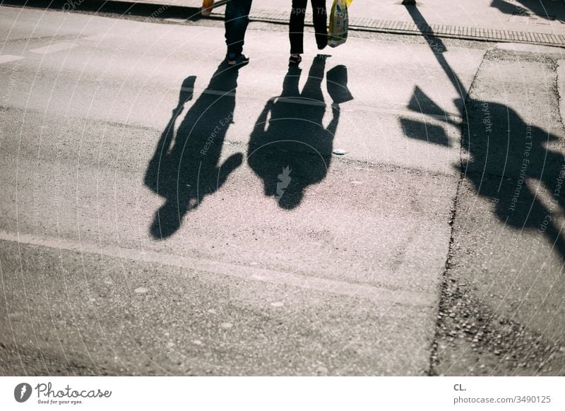 Silhouette of man walking with a cane, long shadow on pavement