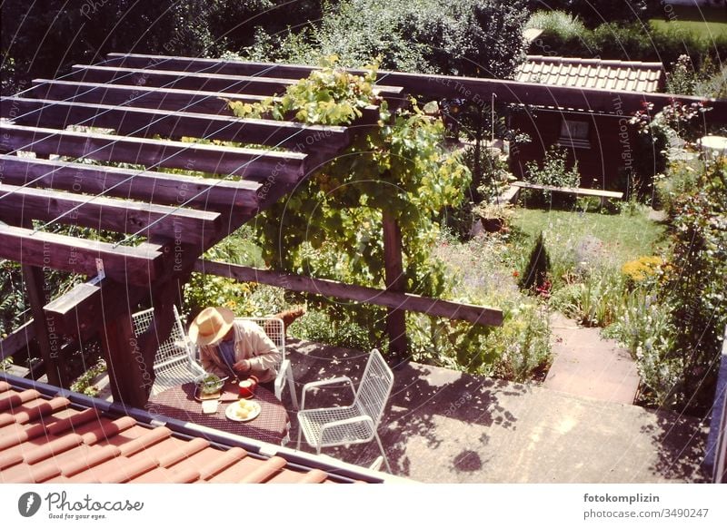 Mann beim Essen auf Terrasse mit Blick von oben Terasse Single allein Witwer Gartenleben Einsamkeit Loneliness Individual Human being lonely lonelyness Laube