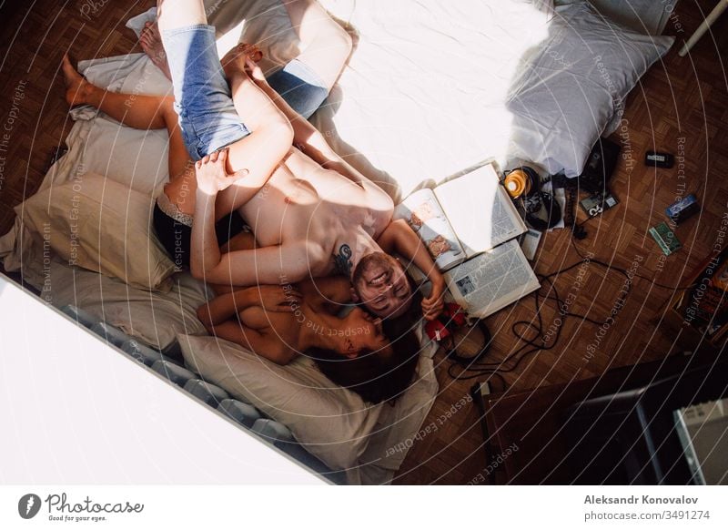 Young funny couple laughs lie on a floor with pillows and vintage books and headphones laughing headpones mc nude anatomy sunlight shadow Youth (Young adults)