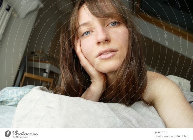 Portrait of a young woman lying in bed in the morning Long-haired Joie de vivre (Vitality) Simple Young woman fringe hairstyle Looking into the camera pretty