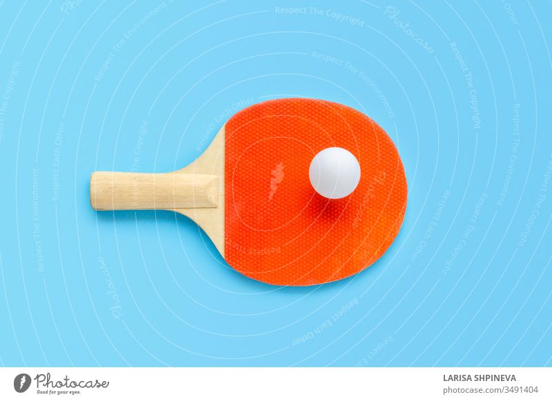 Red racket for table tennis with white ball on blue background. Ping pong sports equipment in minimal style. Flat lay, top view, copy space ping handle game