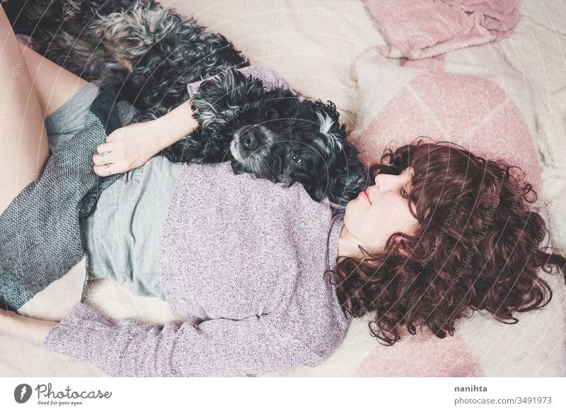 Young woman lying down with her dog pet family love happiness home rest resting together happy casual real real people domestic domestic animal mammal bed
