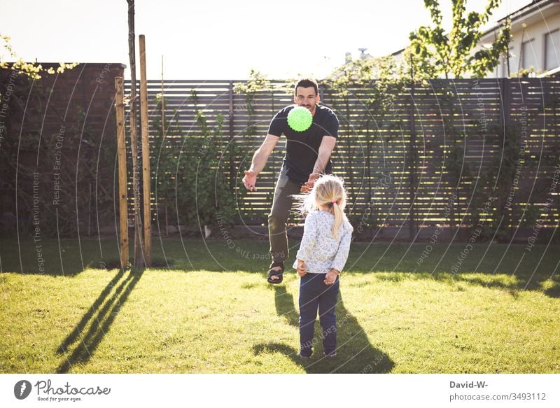 Child and father play in the garden with a ball throwing and catching Girl Man Daughter Father Playing Ball Throw Catch Garden occupy fun Laughter Joy Flying