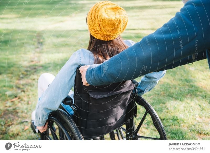 Volunteer pushes the wheelchair of a young disabled girl in a ga accessibility disability woman volunteer happiness optimism mobility handicapped activity