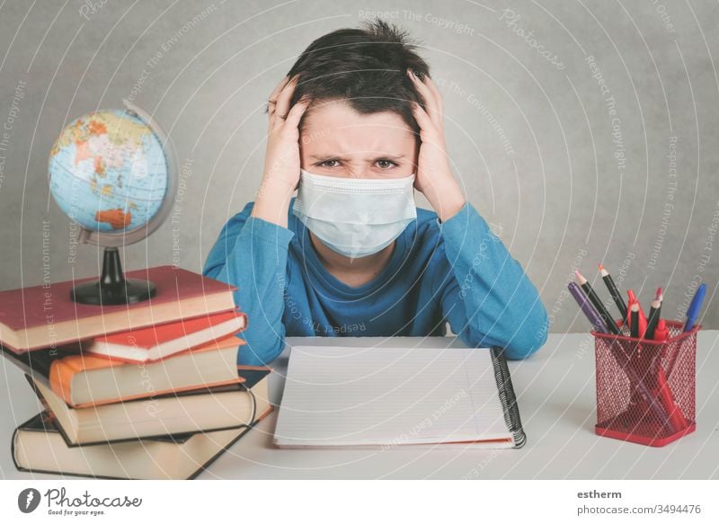 angry child wearing medical mask fed up with doing homework in the quarantine coronavirus epidemic pandemic stay home covid-19 student reading book education